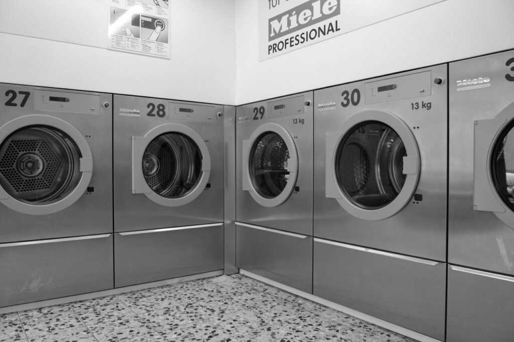 Enlever une tache sur un vêtement : les bons réflexes avant le pressing A sleek row of industrial washing machines in a modern laundromat, conveying efficiency and cleanliness.