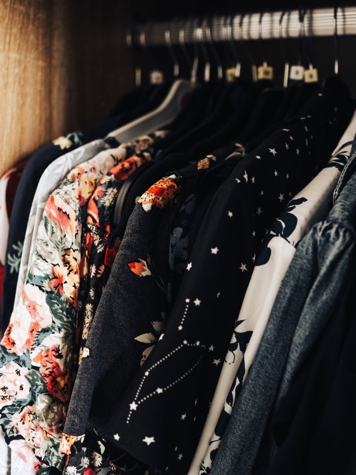 Elegantly arranged clothes in a wardrobe showcasing floral and patterned dresses on hangers.