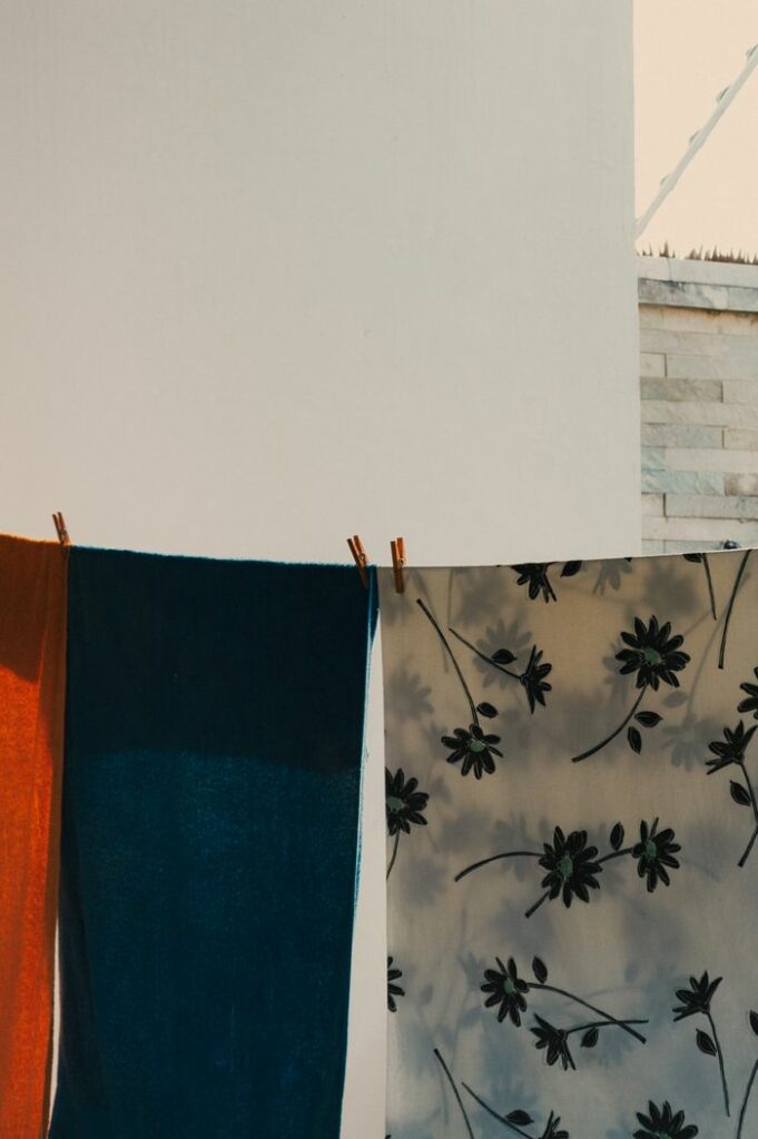 Vibrant towels and fabric with floral pattern drying in the sun outdoors.